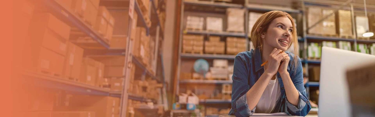 Woman on computer smiling in print warehouse